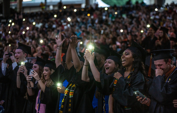 Image of high school seniors in graduation dress taking photos with their phones