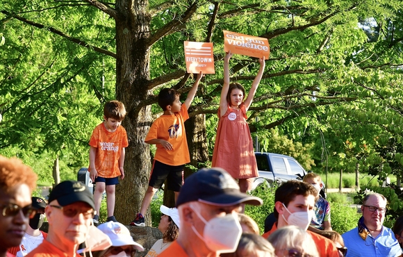 Image of crowd wearing orange shirts and three children holding signs about gun violence awareness
