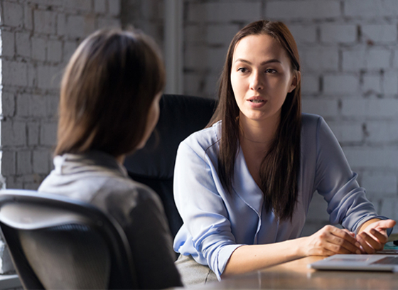 two woman talking at desk