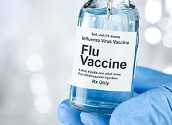 Gloved hand holding vial of flu vaccine