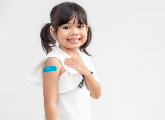Young girl with pigtails shows the band-aid on her upper arm