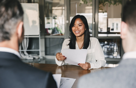 woman sitting at desk across from two men