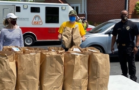 Volunteers holding brown paper bags of groceries